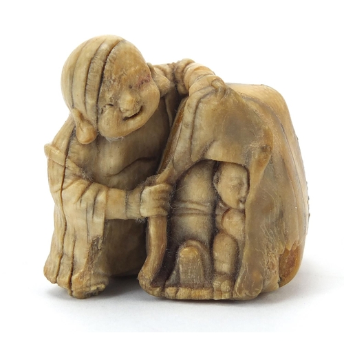 205 - ** WITHDRAWN ** Japanese carved ivory netsuke of a man and figure hiding, character marks to the und... 