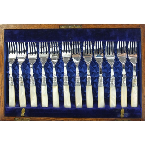 1083 - Oak twelve place canteen of silver plated fish knives and forks with mother of pearl handles, the ca... 