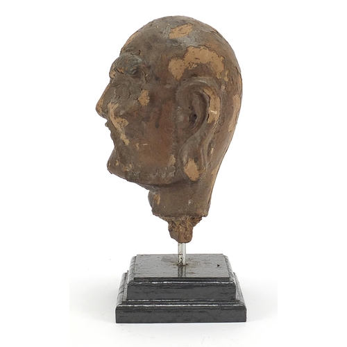 479 - Chinese stucco head raised on a later stepped rectangular plinth base, 28.5cm high