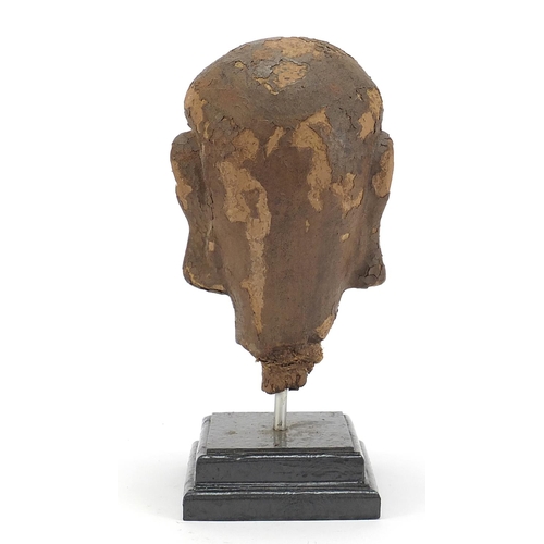 479 - Chinese stucco head raised on a later stepped rectangular plinth base, 28.5cm high