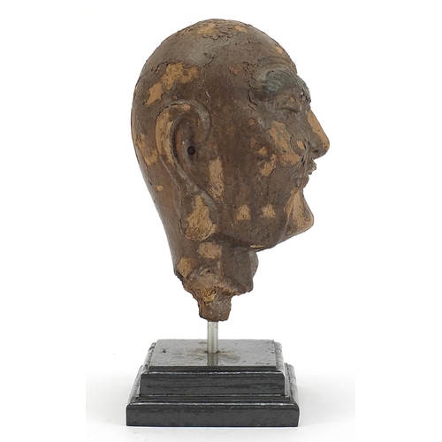 479 - Chinese stucco head raised on a later stepped rectangular plinth base, 28.5cm high