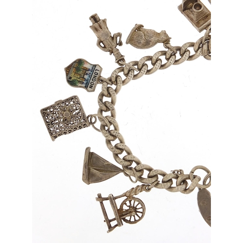 985 - Silver charm bracelet with a selection of mostly silver charms including Flying Doctor aeroplane, ba... 