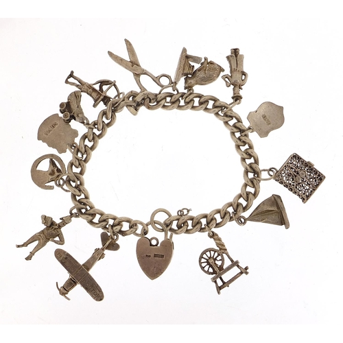 985 - Silver charm bracelet with a selection of mostly silver charms including Flying Doctor aeroplane, ba... 