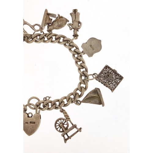 985 - Silver charm bracelet with a selection of mostly silver charms including Flying Doctor aeroplane, ba... 