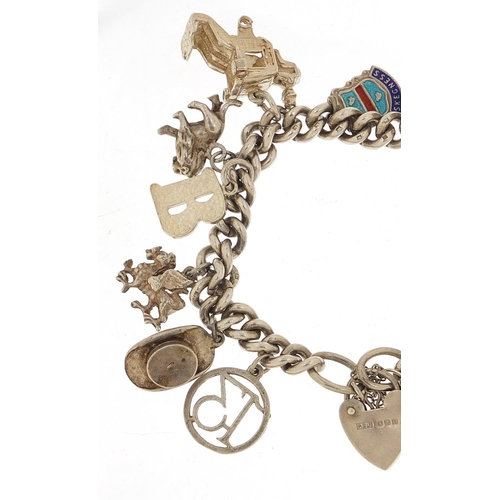 455 - Silver charm bracelet with a selection of mostly silver charms including a top hat, lion, dragon and... 