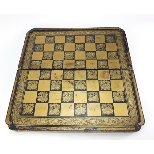 135 - Chinese black lacquered folding chess/games board, finely gilded with figures, flowers and dragons, ... 