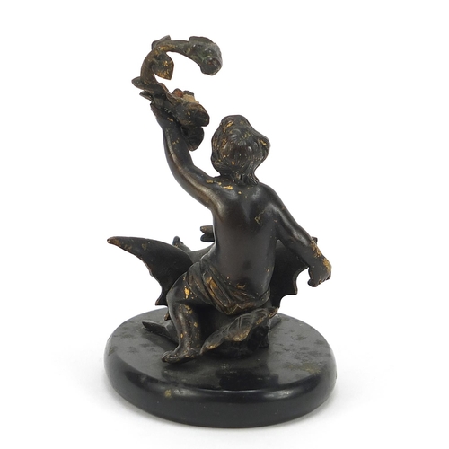 147 - Cold painted bronze figure of Putti on a swan raised on an oval slate base, 11cm high