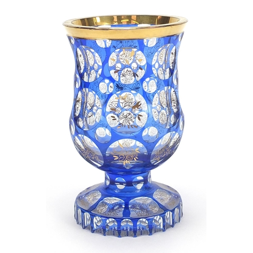 84 - Bohemian blue flashed glass goblet vase gilded with flowers and instruments, 16cm high