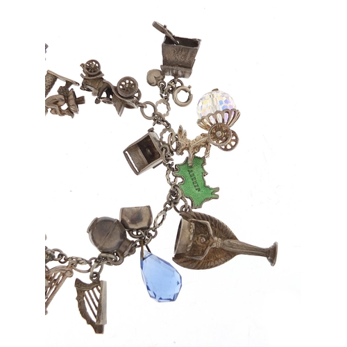 745 - Silver charm bracelet with a large selection of charms including a 1966 World Cup trophy, Putti play... 