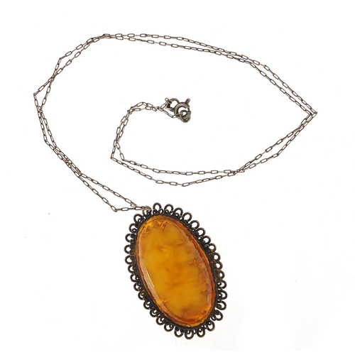 1122 - Large silver mounted amber pendant on a silver chain, the pendant 5cm high, total 15.8g