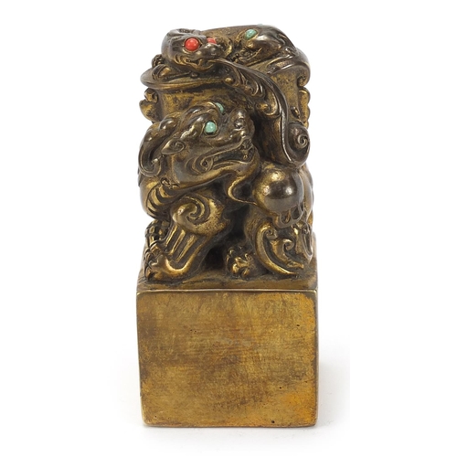 168 - Chinese patinated bronze dog of Foo seal set with turquoise and coral coloured stones, 12cm high