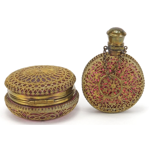 119 - Antique cranberry glass scent bottle and compact with brass foliate overlay housed in a silk lined f... 