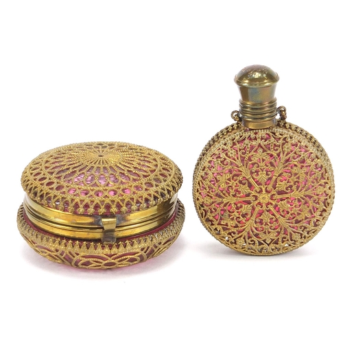 119 - Antique cranberry glass scent bottle and compact with brass foliate overlay housed in a silk lined f... 