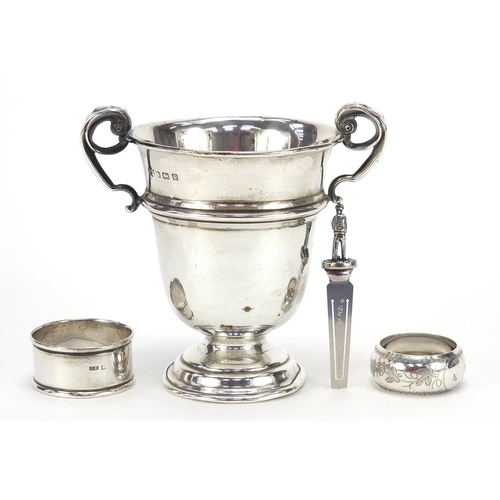 515 - Golfing interest silver trophy with twin handles, two silver napkin rings and a bookmark, the trophy... 