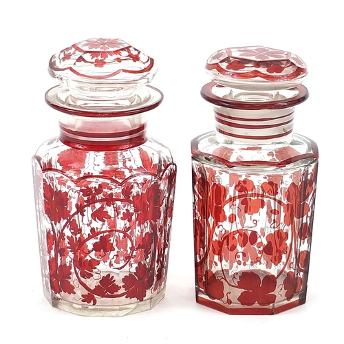 74 - Matched pair of Bohemian glass jars and covers decorated in ruby with foliage, the largest 16cm high