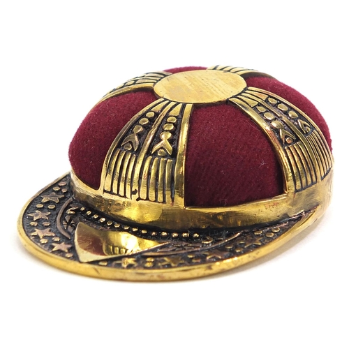 2076 - Novelty brass pin cushion in the form of a jockey's cap, 5cm in length