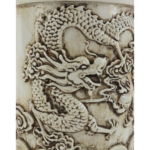 637 - Chinese porcelain brush pot decorated in relief with a dragon amongst clouds, impressed character ma... 