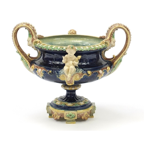 290 - 19th century Majolica centrepiece with twin handles  surmounted with two Putti, 27.5cm high x 33.5cm... 