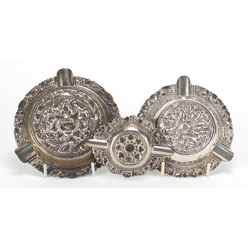 935 - Three 800 silver ashtrays profusely embossed with flowers, possibly Indian, the largest 12cm in diam... 