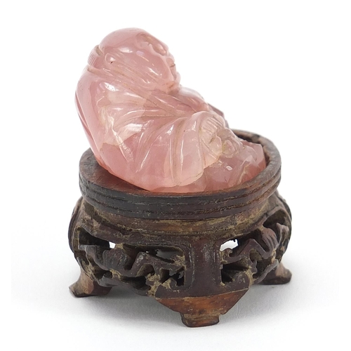 257 - Chinese rose quartz carving of Buddha raised on a carved hardwood stand, 5.5cm wide