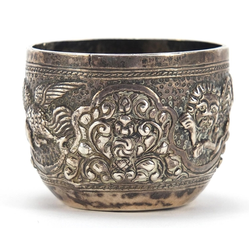 390 - Tibetan silver cup profusely embossed with birds and wild animals amongst foliage, 3.5cm high, 44.4g