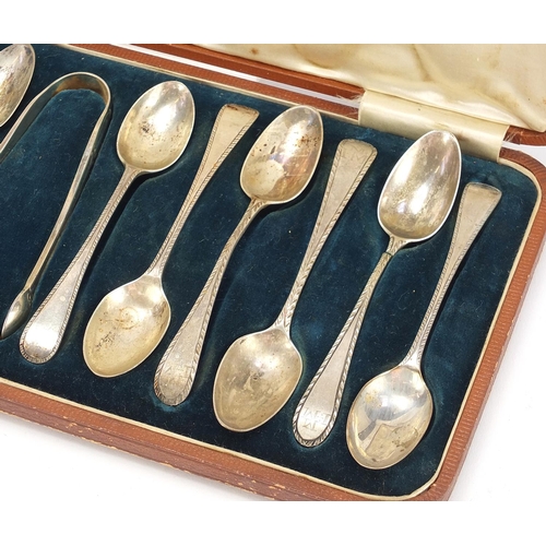 1121 - Matched set of twelve silver teaspoons and silver plated sugar tongs housed in a velvet and silk lin... 