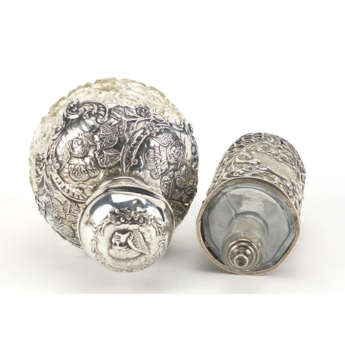 790 - Henry Matthews, two Edwardian silver overlaid cut glass scent bottles embossed with Putti and foliag... 