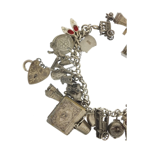 562 - Heavy silver charm bracelet with a large selection of mostly silver charms including bibles, fire en... 