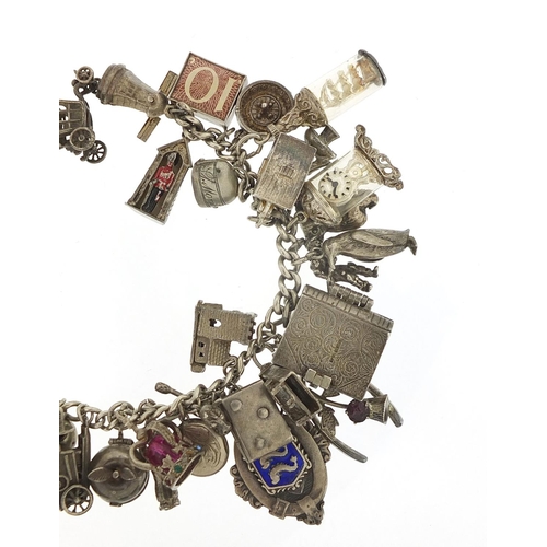 562 - Heavy silver charm bracelet with a large selection of mostly silver charms including bibles, fire en... 