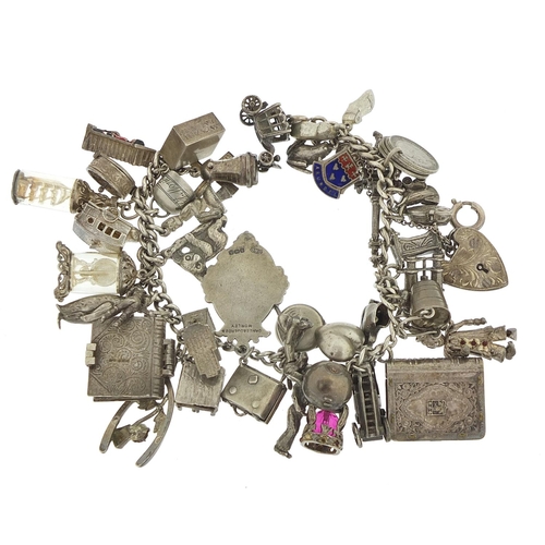 562 - Heavy silver charm bracelet with a large selection of mostly silver charms including bibles, fire en... 