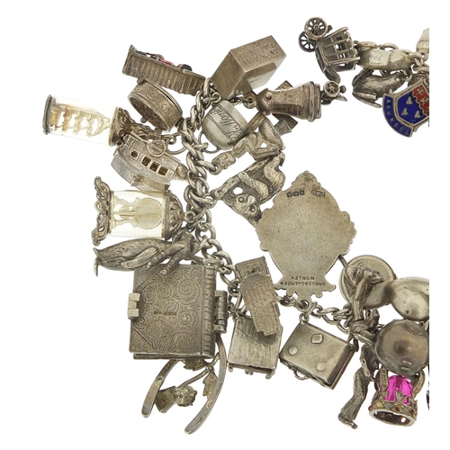 562 - Heavy silver charm bracelet with a large selection of mostly silver charms including bibles, fire en... 