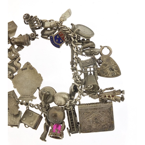 562 - Heavy silver charm bracelet with a large selection of mostly silver charms including bibles, fire en... 