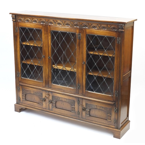 1021 - Reprodux oak bookcase fitted with three leaded glass doors encloding adjustable shelves and three cu... 