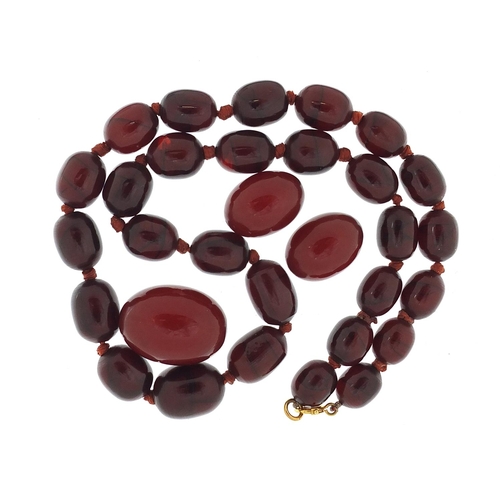 65 - Cherry amber coloured bead necklace and three beads, the necklace 48cm in length, total 49.7g