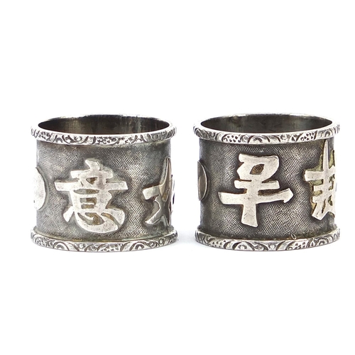 602 - Pair of Chinese silver coloured metal napkin rings decorated with script, 2cm high, 17.0g