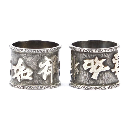 602 - Pair of Chinese silver coloured metal napkin rings decorated with script, 2cm high, 17.0g