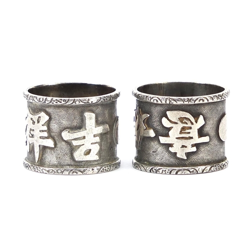 602 - Pair of Chinese silver coloured metal napkin rings decorated with script, 2cm high, 17.0g