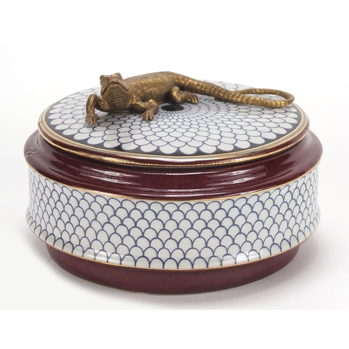 2458 - Continental porcelain box and cover surmounted with a bronze lizard, 13.5cm in diameter