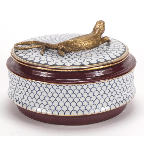 2458 - Continental porcelain box and cover surmounted with a bronze lizard, 13.5cm in diameter