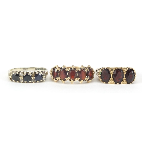 126 - Three 9ct gold rings comprising two with garnets and one with sapphires and diamonds, sizes L, Q and... 