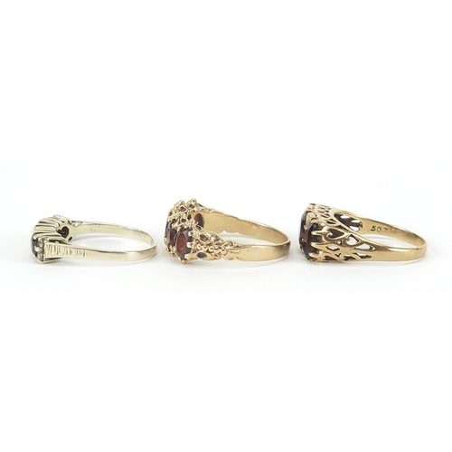 126 - Three 9ct gold rings comprising two with garnets and one with sapphires and diamonds, sizes L, Q and... 