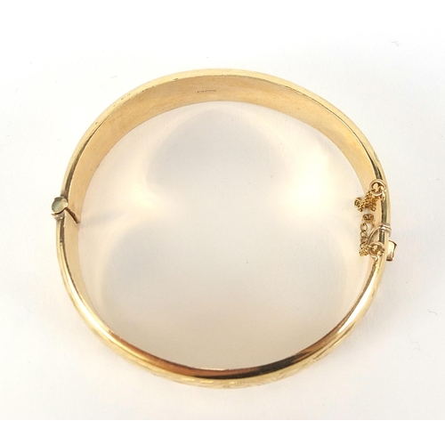 125 - 9ct gold hinged bangle with engraved decoration, Birmingham 1994, 6.2cm in diameter, 1.5cm wide, 17.... 