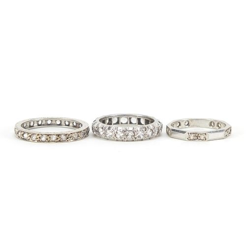 354 - Three unmarked white metal clear stone eternity rings, sizes I and M, 6.4g