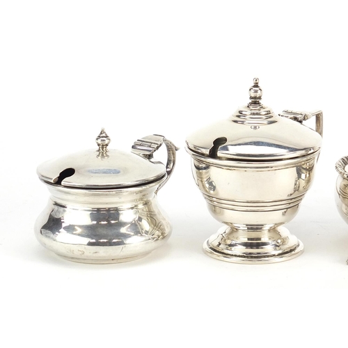 2433 - Three Edwardian and later silver mustards with hinged lids and an open salt, two with blue glass lin... 