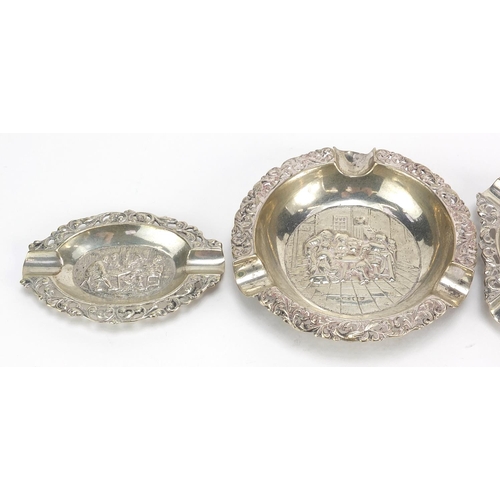 2327 - Three Dutch silver ashtrays embossed with figures in a tavern and one other, the largest 9.5cm in di... 