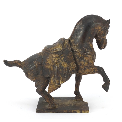 1092 - Chinese cast iron horse with one raised foreleg, standing on a metal plinth, 23cm in length