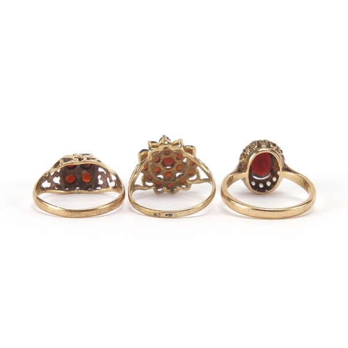 1763 - Three 9ct gold garnet rings including one set with clear stones, sizes K, L and M, 6.0g