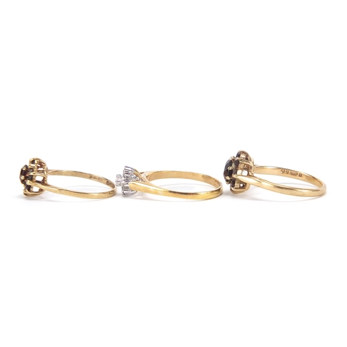 1715 - Two 9ct gold garnet cluster rings and a gold coloured metal clear stone ring, sizes K, L and M, 5.6g