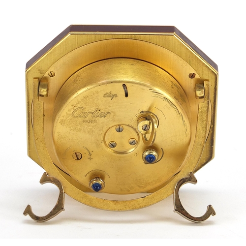 268 - Cartier red and gold coloured desk strut clock, the dial having Roman numerals, housed in a red pres... 