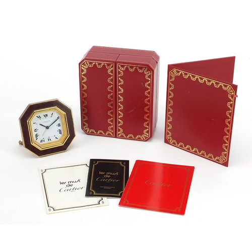 268 - Cartier red and gold coloured desk strut clock, the dial having Roman numerals, housed in a red pres... 